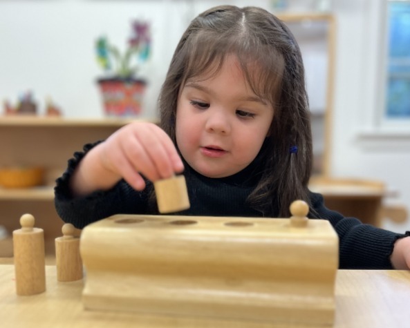 child working with knobbed cylanders