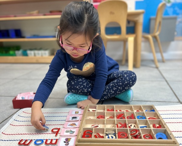 girl using movable alphabet to spell words